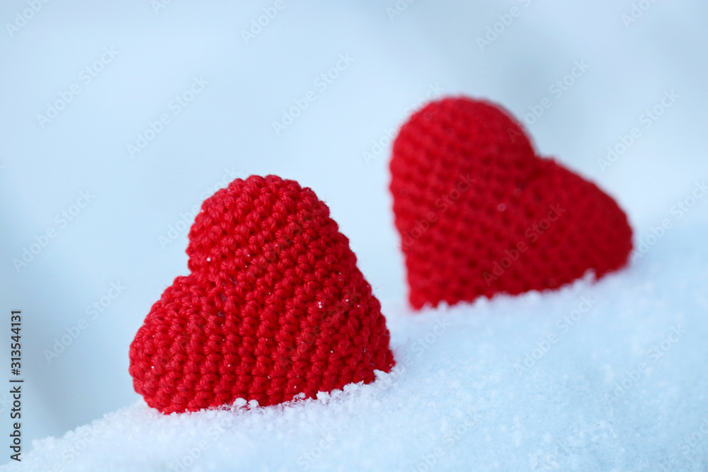Valentine's hearts, greeting card, two red knitted symbols of love in the snow. Background for romantic event, celebration or winter weather Valentine's hearts, greeting card, two red knitted symbols of love in the snow. Background for romantic event, celebration or winter weather