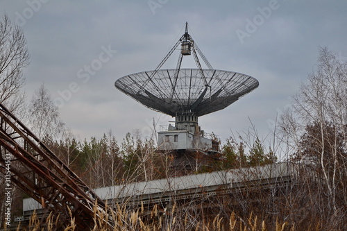 Old radio antenna in the forest. Astronomy and space research. photo