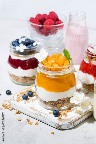 desserts with muesli, fresh berries and fruit in jars, vertical