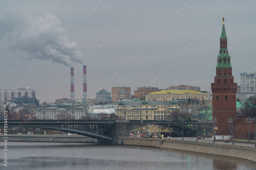 Moscow downtown cityscape. Kremlin Towers, Bolshoy Kamenny Bridge and Heat station pipes in overcast winter day. The concept of combining past and present