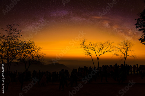 Starry sky scene on high mountains with people taking photograph of Scenic sunrise with milky way.