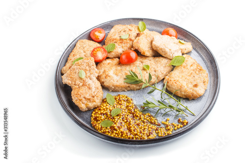 Fried pork chops with tomatoes and herbs on a gray ceramic plate isolated on white background. side view.