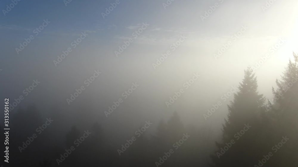 Drone rises over a foggy landscape on a beautiful blue sky day with mottled clouds to reveal a mountain vista Drone rises over a foggy landscape on a beautiful blue sky day with mottled clouds to reveal a mountain vista