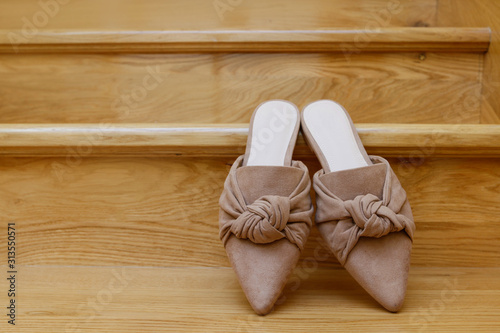 A pair of mule shoes on wooden stairs.