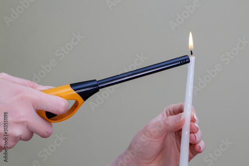 A woman lights a candle using a lighter.