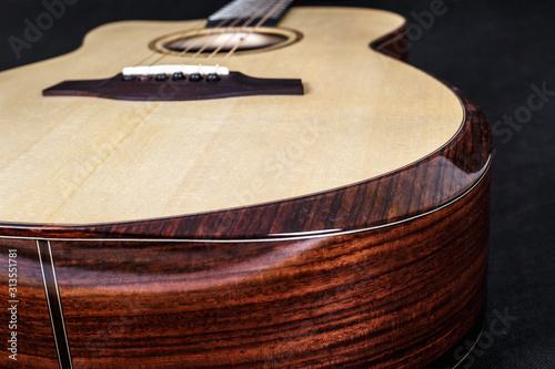 wood texture of lower deck of six strings acoustic guitar on black background. guitar shape