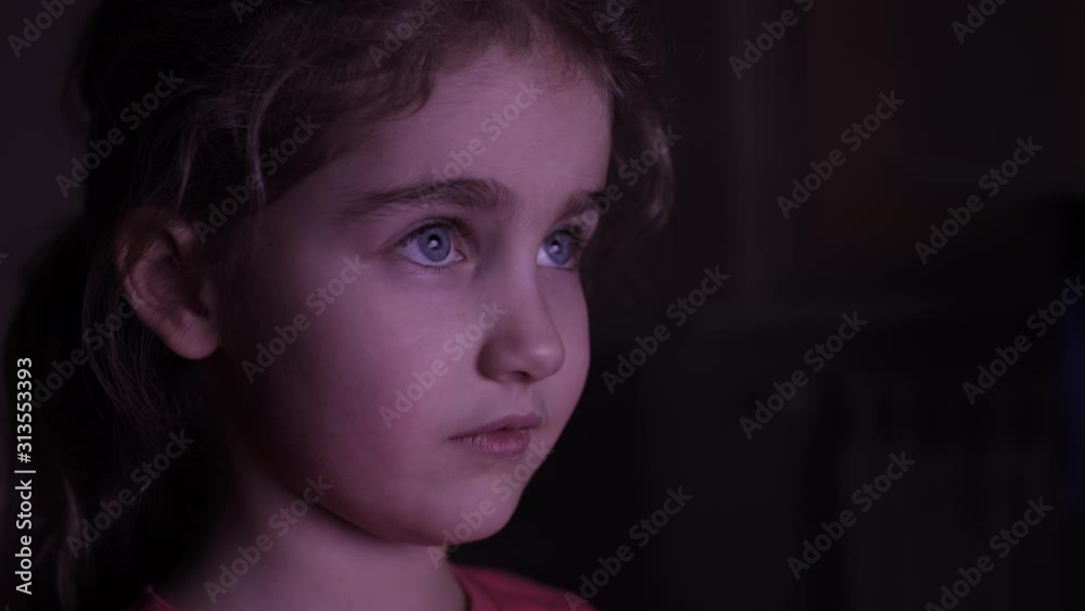 Portrait Сute Little Kid While Watching TV. Young Girl Watch Television on Living Room. Concept Video Game, Entertainment, Emotions, Family. Child Watching TV, Close up Face of Little Girl, Kid Eyes. Portrait Сute Little Kid While Watching TV. Young Girl Watch Television on Living Room. Concept Video Game, Entertainment, Emotions, Family. Child Watching TV, Close up Face of Little Girl, Kid Eyes.