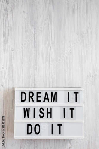 'Dream it, wish it, do it' words on a lightbox on a white wooden surface, top view. Overhead, from above, flat lay. Copy space.