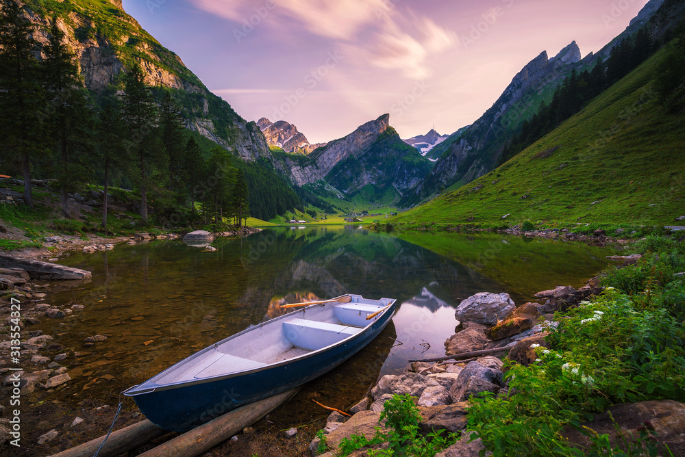 Sunset over the Seealpsee lake with a boat in the Swiss Alps, Switzerland