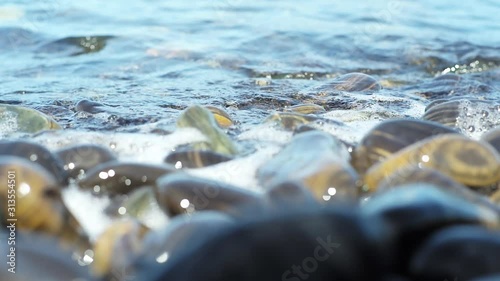 Selective focus on group of pebble stones were surfed by the sea wave in sunny day