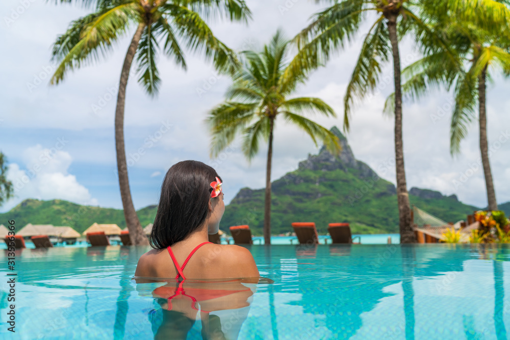 Hotel resort vacation tourist swimming in hotel pool enjoying view of famous French Polynesia honeymoon travel destination icon - Otemanu peak mount in Bora Bora island, Tahiti luxury stay getaway.
