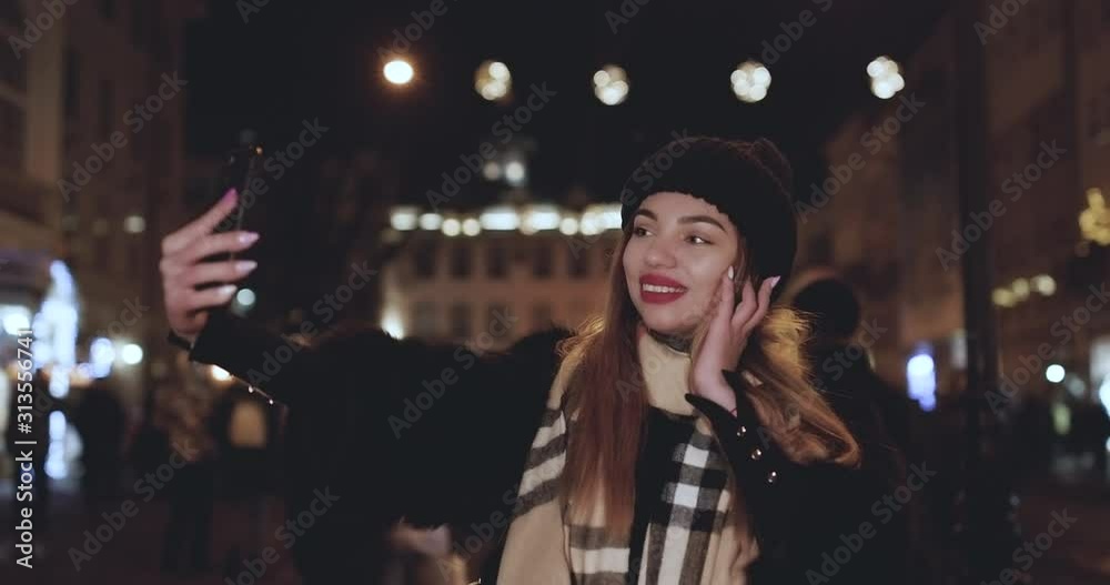 Happy Caucasian girl making selfie. Stylishly dressed model girl posing on the streets of the city.