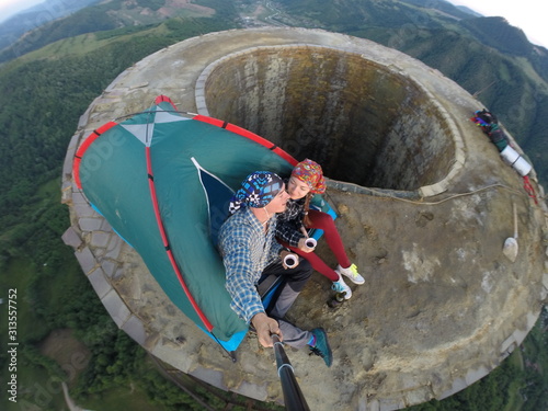 Urban climbers taking a selfie after waking up on top of an abandoned industrial smock stack chimney, sleeping in a tent, life risking adventure photo