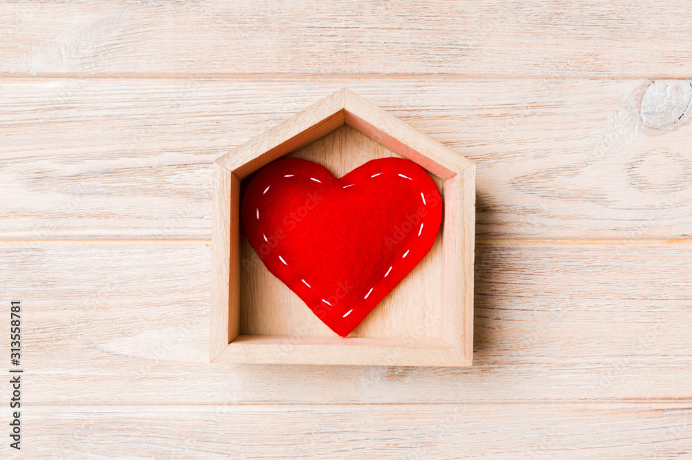 Top view of red textile heart in a house on wooden background. Home sweet home concept. Valentine's day Top view of red textile heart in a house on wooden background. Home sweet home concept. Valentine's day