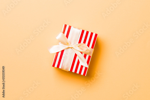 Top view Christmas present box with yellow bow on orange background with copy space © sosiukin