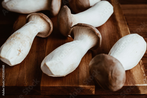 Group of raw King Oyster mushroom (also known as eryngii) on a wooden cutting kitchen board. photo