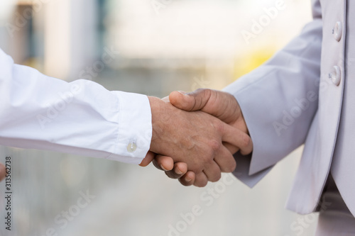 Male and female professionals greeting each other in city. Closeup of business man and woman shaking hands outside. Dealing or trust concept