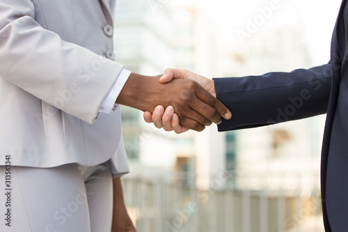 Multiethnic female professionals greeting each other in city. Closeup of business women shaking hands outside. Teamwork or success concept