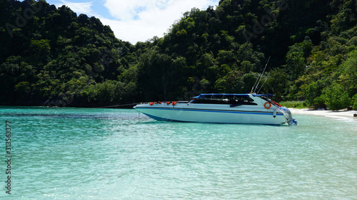 White color speed boat parking on the water with beautiful beach background © augustcindy