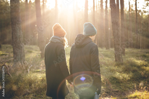 Couple in warm clothing taking a walk inside a sunny forest photo