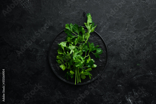 Fresh green parsley on black stone background. Vegetables. Top view. Free space for your text.