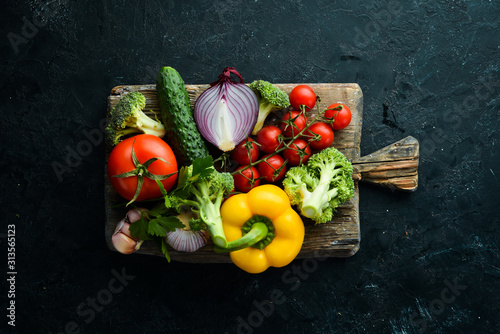 Ripe vegetables. Fresh vegetables on black stone background. Tropical fruits. Top view. Free space for your text.