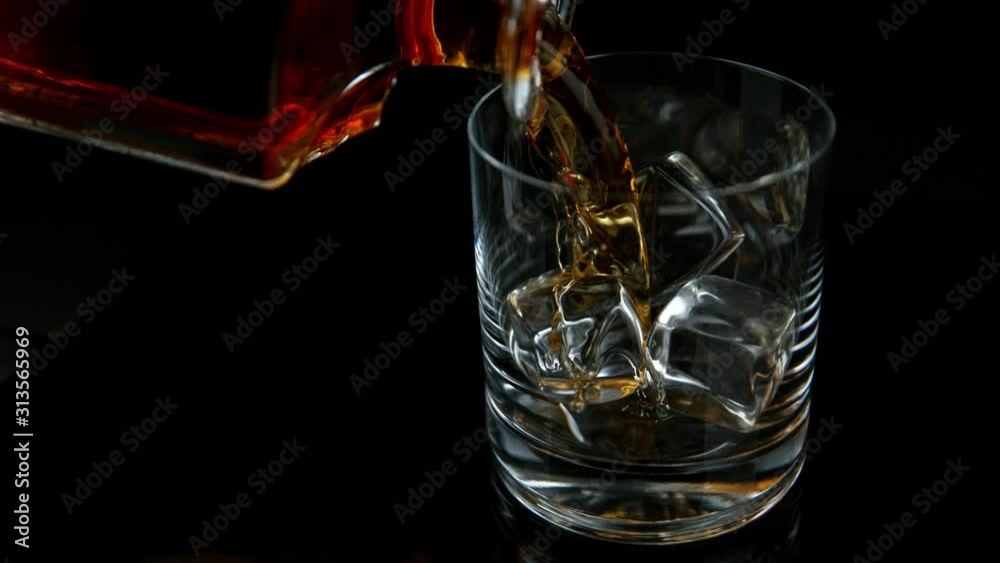Super Slow Motion Shot of Pouring Whiskey from Bottle into Glass with Ice Cubes at 1000fps with Camera Movement. Super Slow Motion Shot of Pouring Whiskey from Bottle into Glass with Ice Cubes at 1000fps with Camera Movement.