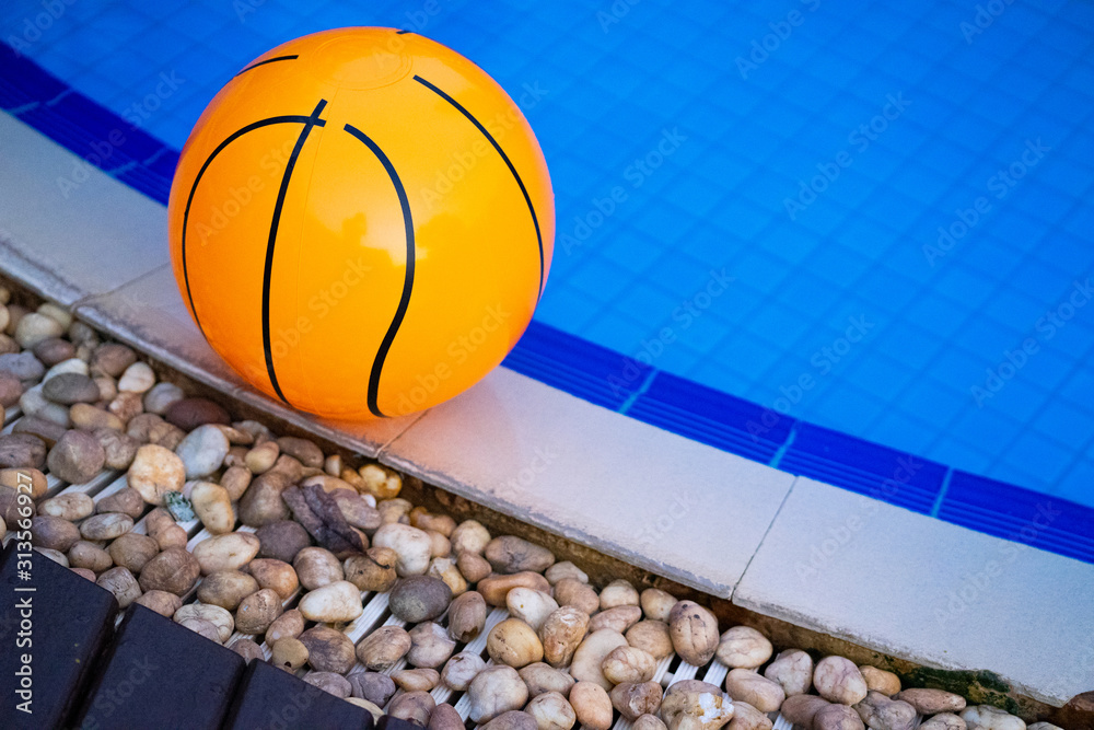 An orange ball is placed by the pool in the hotel.
