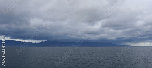 Cloudy day at sea and dark rain clouds on the background of the island