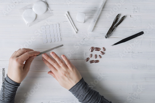 The process of putting artificial (fake) fingernail on the finger. Woman manicure. Flat lay.