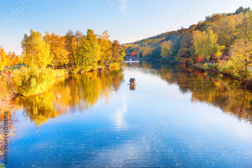 Lake in park with small house and autumn forest and trees