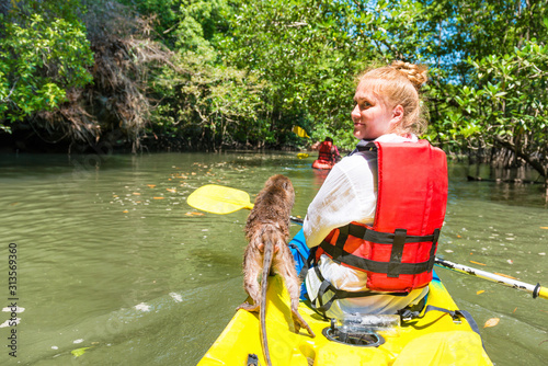 Photography Young woman kayaking on canoe with wild monkey