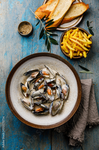 Shellfish Mussels Clams with cheese creamy sauce and French Fries on blue wooden background