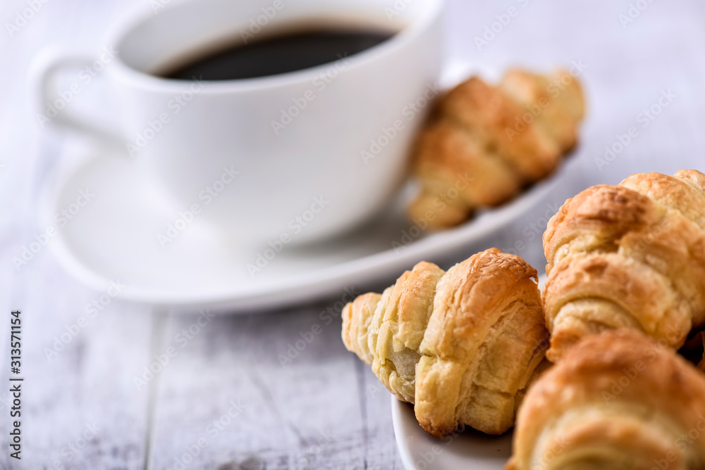 Cup of coffee on wooden tray with croissants.