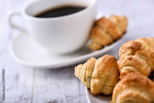 Cup of coffee on wooden tray with croissants.