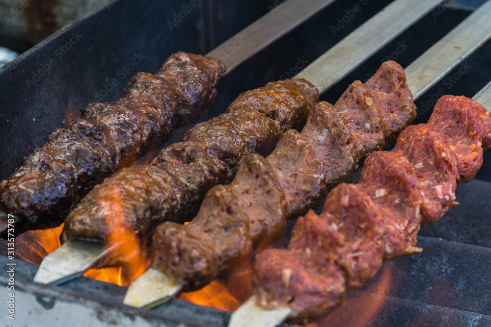 Adana kebab (ground lamb minced meat on skewer on grill over charcoal).Chef preparing traditional authentic Turkish shaworma. Middle eastern cuisine. Handmade specialty street food market with spices