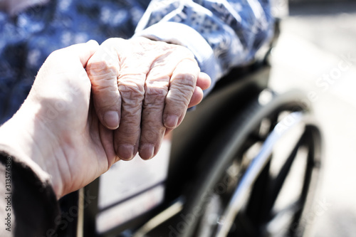 Close up of hands of aged woman sitting in the wheelchair outdoors