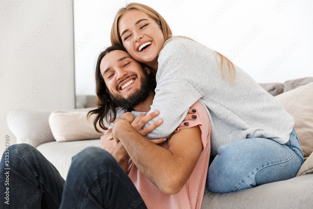Young loving couple on sofa hugging.