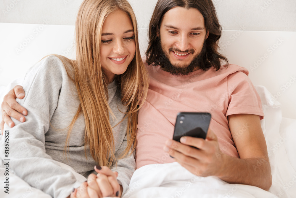 Beautiful young couple sitting in bed at home Beautiful young couple sitting in bed at home
