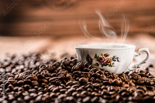 Fresh coffee beans with white cup on wooden background.