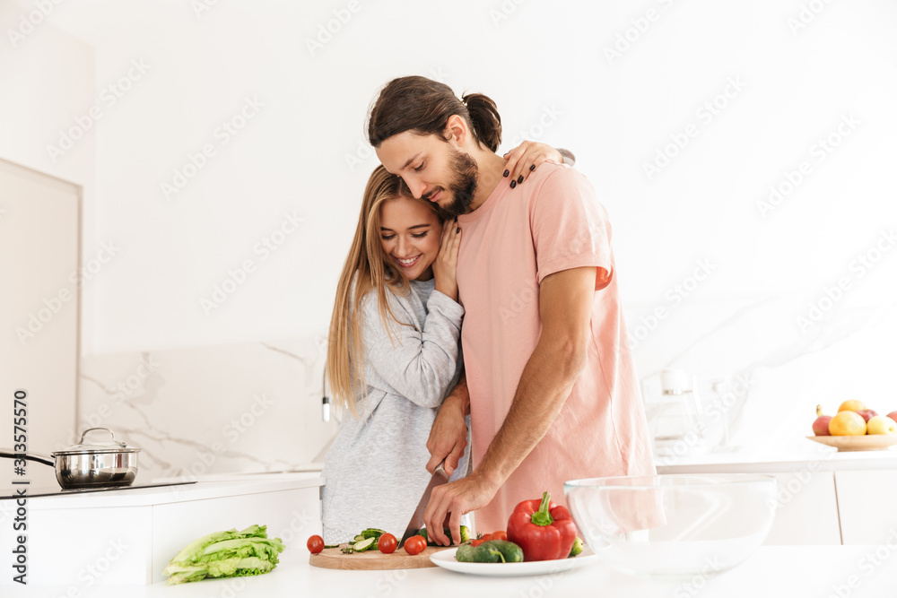 Cheerful lovely couple cooking healthy meal together Cheerful lovely couple cooking healthy meal together