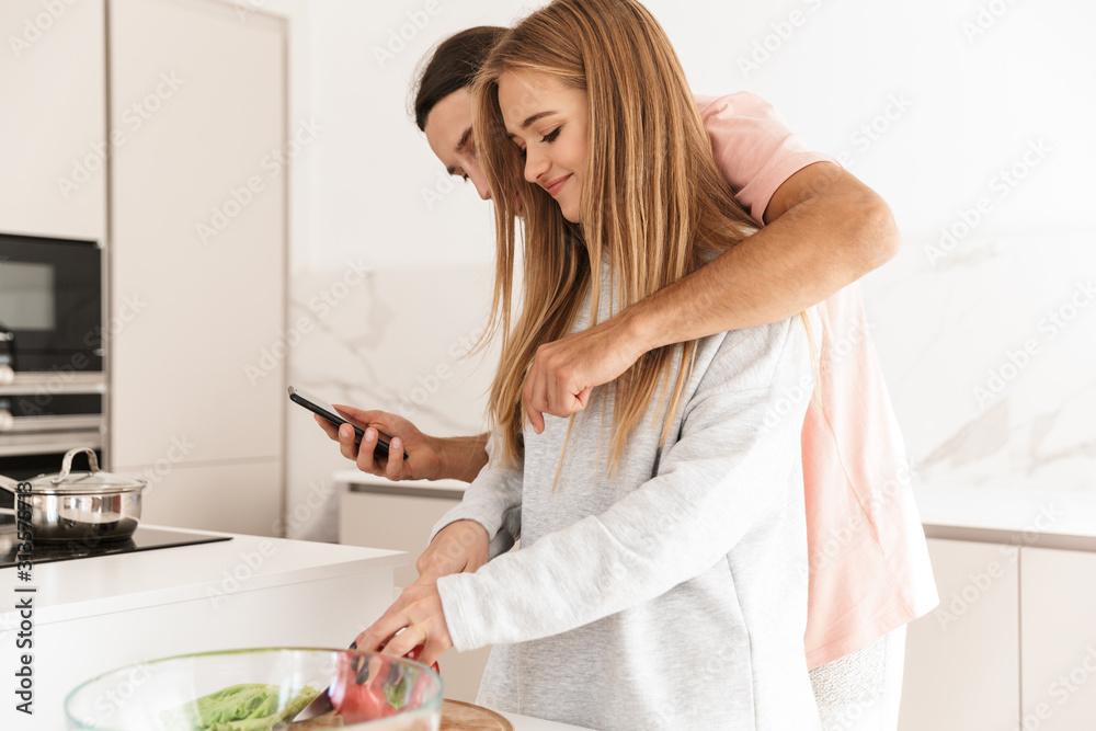 Loving couple at the kitchen using mobile phone Loving couple at the kitchen using mobile phone