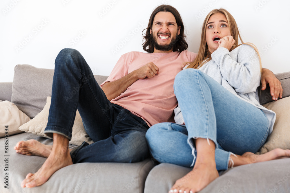 Scared young loving couple on sofa watch tv Scared young loving couple on sofa watch tv