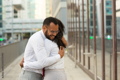 Free Download Joyful old friends meeting and hugging outside. Multiethnic couple standing in city street and embracing each other. Friendship concept - GFXLoad