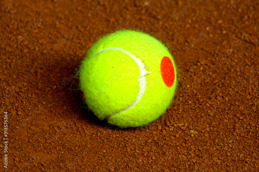 A green tennis ball on red grundslag