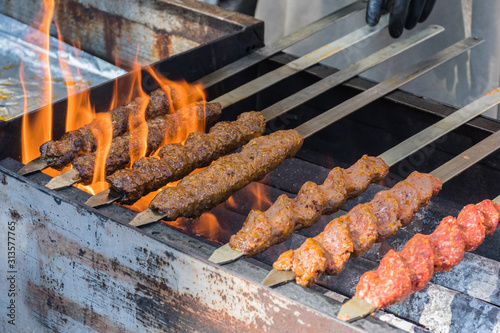 Adana kebab (ground lamb minced meat on skewer on grill over charcoal).Chef preparing traditional authentic Turkish shaworma. Middle eastern cuisine. Handmade specialty street food market with spices