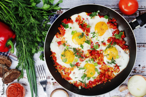 Shakshouka with five cooked eggs on top of tomato sauce in cast iron skillet 