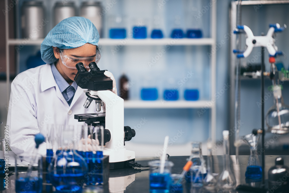 Young scientist looking through a microscope in a laboratory. Young scientist doing some research. Young scientist looking through a microscope in a laboratory. Young scientist doing some research.