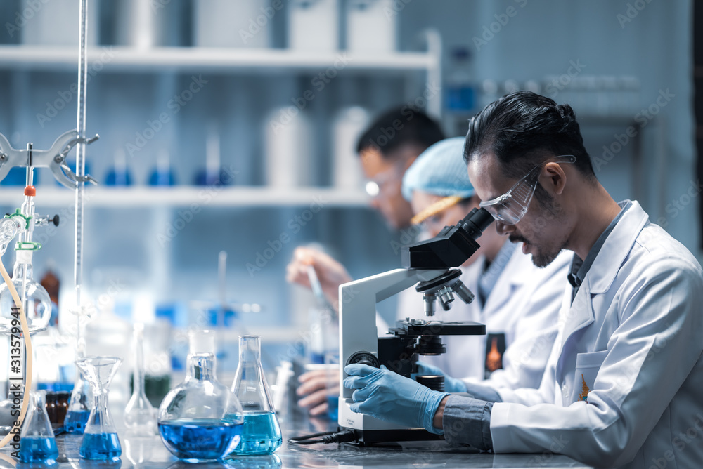 Young scientist looking through a microscope in a laboratory. Young scientist doing some research. Young scientist looking through a microscope in a laboratory. Young scientist doing some research.
