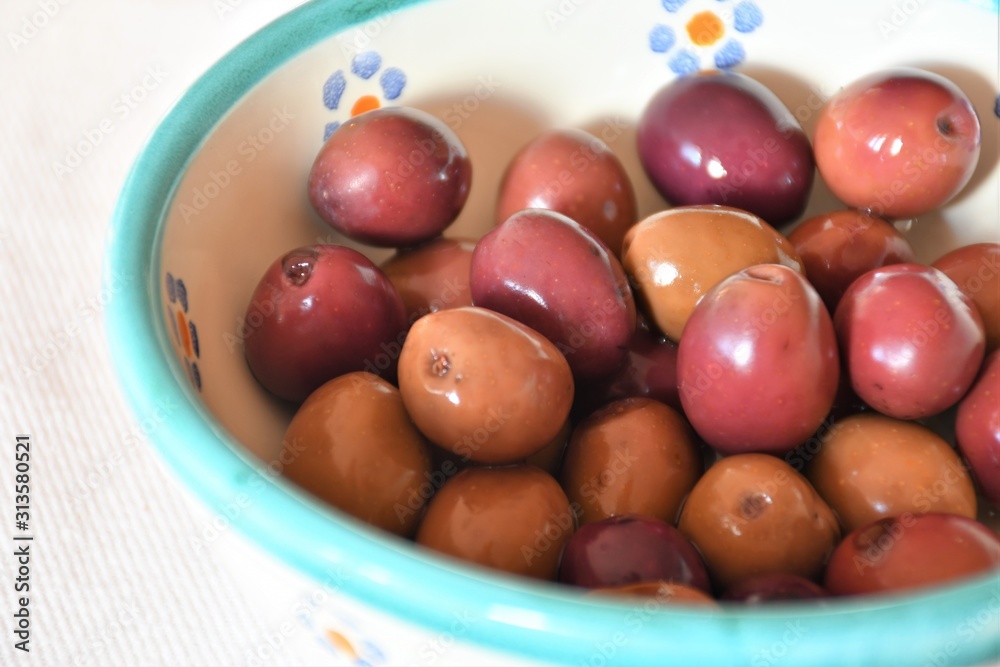 Typical Italian and Apulian salty and briney olives cured with an aromatic herb brine of rosemary, bay leaves and thyme, traditional snack or appetizer in a terracotta pot Typical Italian and Apulian salty and briney olives cured with an aromatic herb brine of rosemary, bay leaves and thyme, traditional snack or appetizer in a terracotta pot